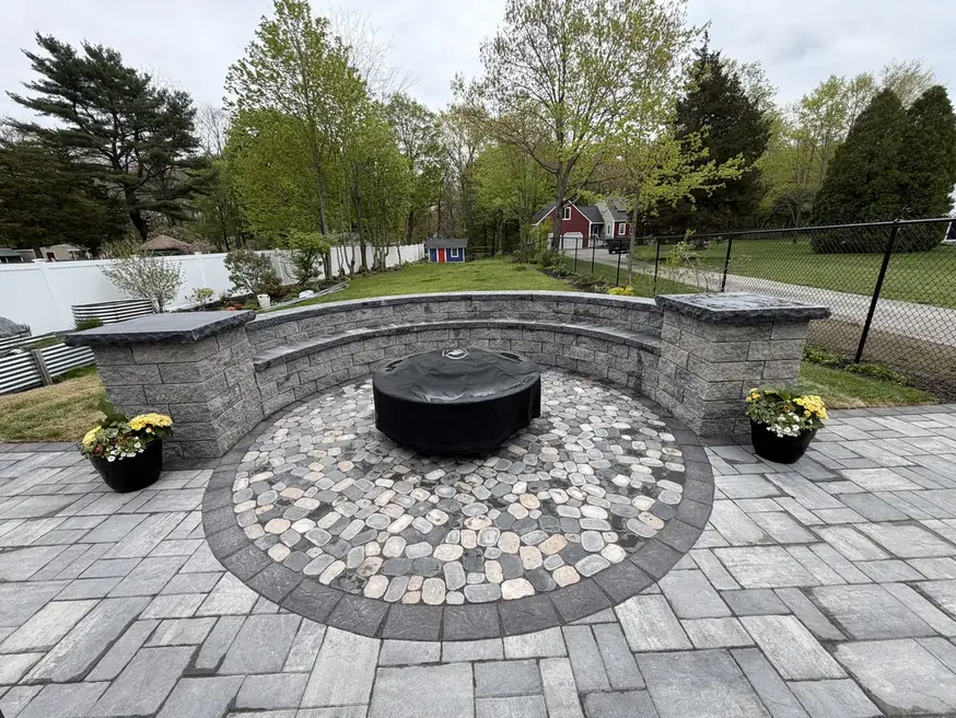 Paver patio with a fire pit, cobblestone circle, and curved seat wall