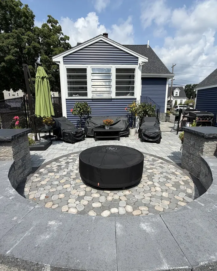 Round fire pit area with a cobblestone circle and a curved stone seat wall