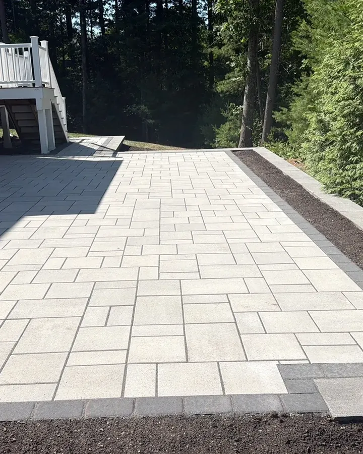 Large-format gray paver patio with a dark border behind a house