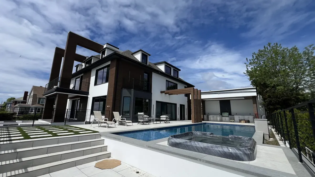 Light paver pool deck with steps and a spa beside a modern home