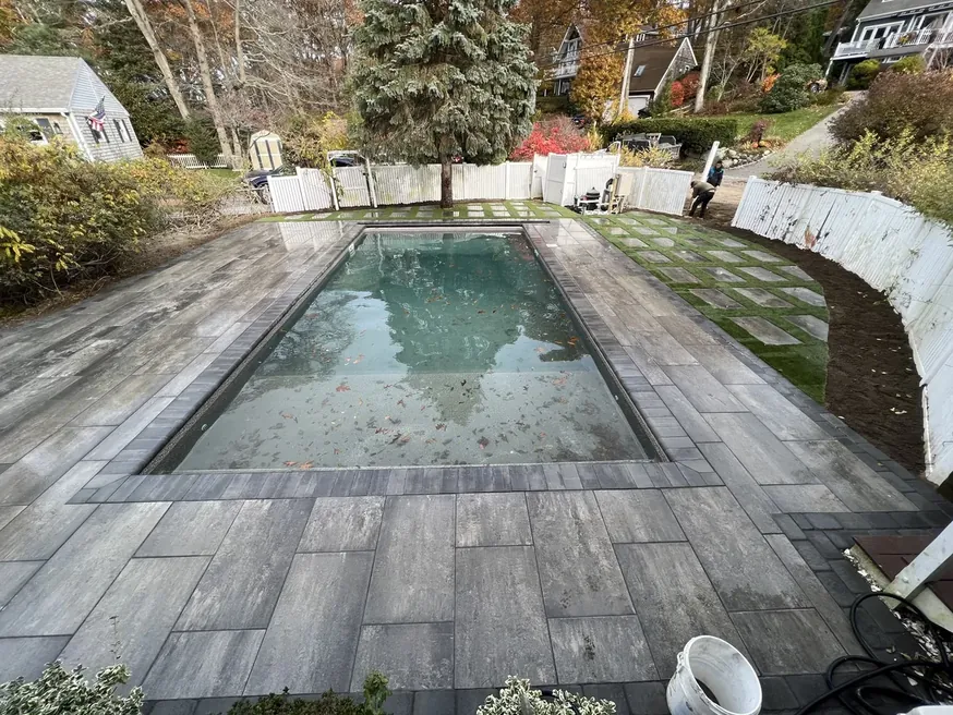 Inground pool surrounded by a new paver pool deck with a dark border
