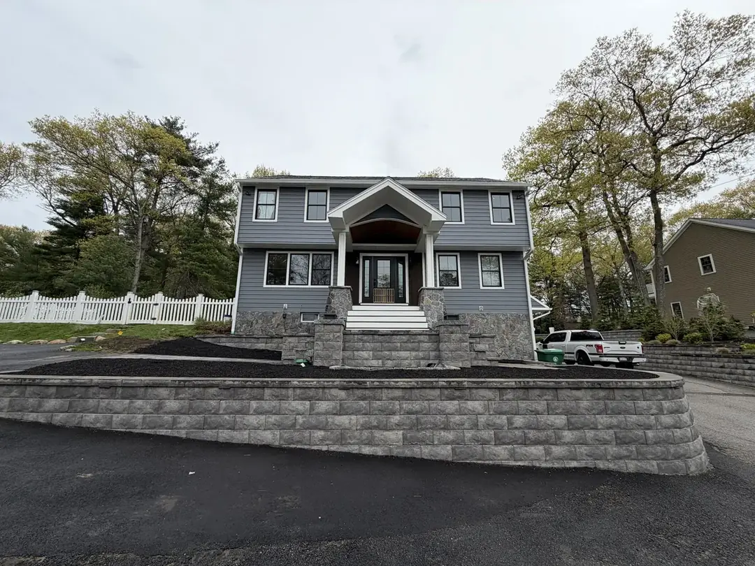 Segmental block retaining wall holding a raised front yard above a paved driveway