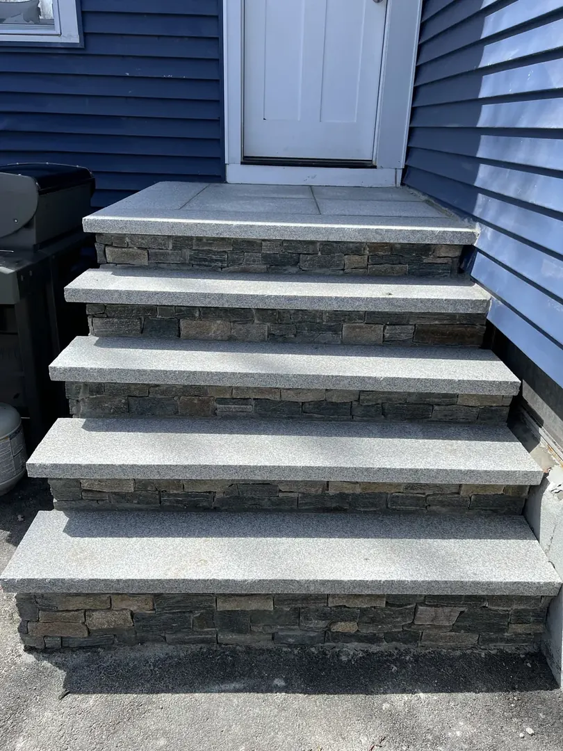 Stone veneer steps with granite treads leading to a front door