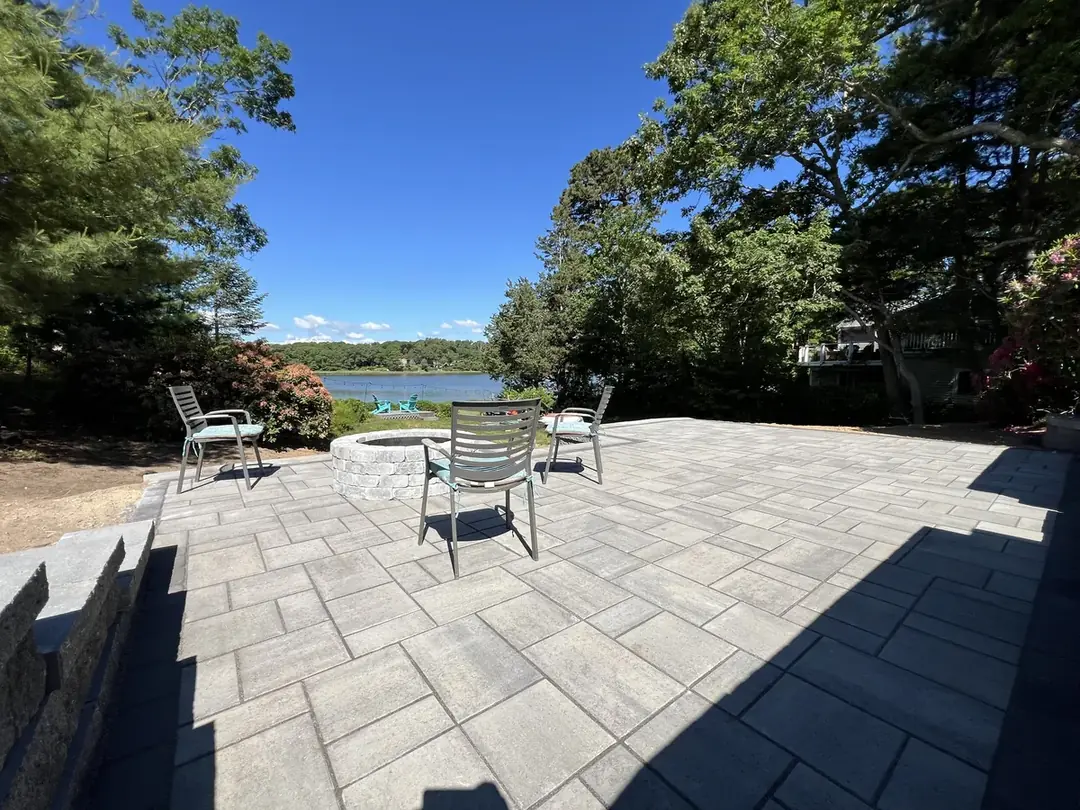 Large gray paver patio with outdoor chairs on a waterfront lot